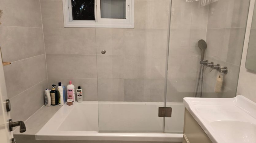 Salle de bain avec baignoire et paroi en verre, appartement renove a Jerusalem
