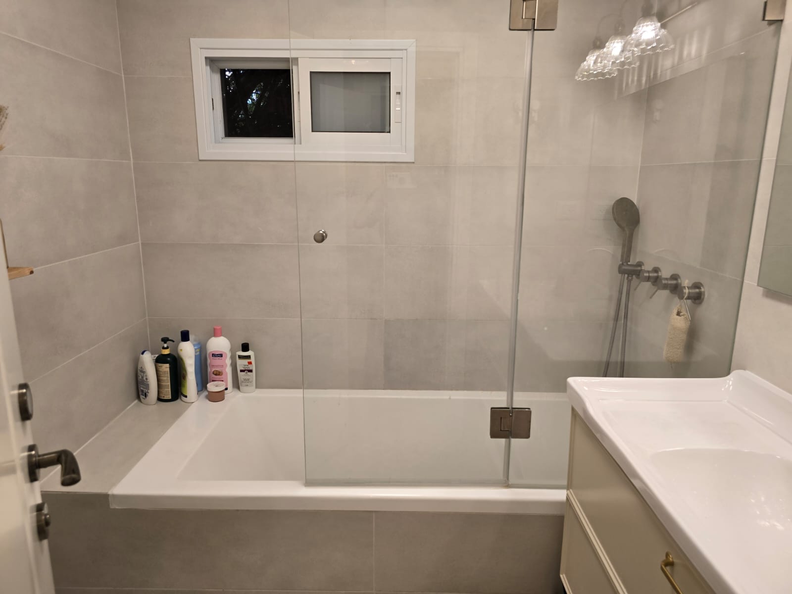 Salle de bain avec baignoire et paroi en verre, appartement rénové à Jérusalem